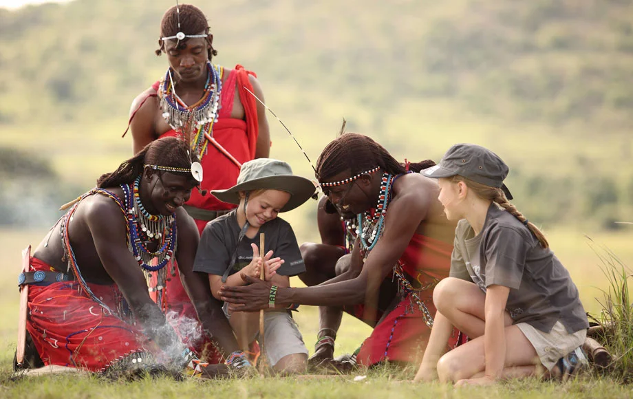 A kid starting fire with help of Maasai warrior